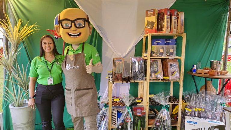 Foto com o Boneco Vieirão junto de uma colaboradora dentro do stand Casa Vieira e Tramontina.