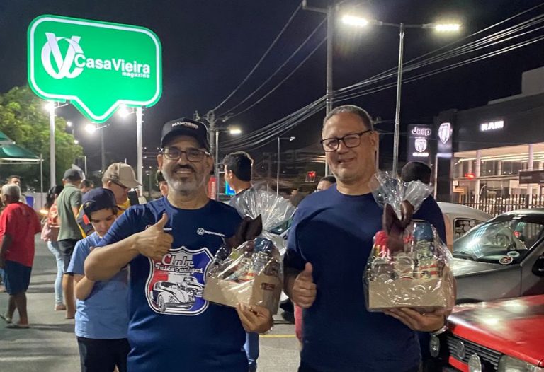 Dois homens em pé lado a lado, cada um segurando uma pequena cesta com prêmios que foram sorteados durante o evento.